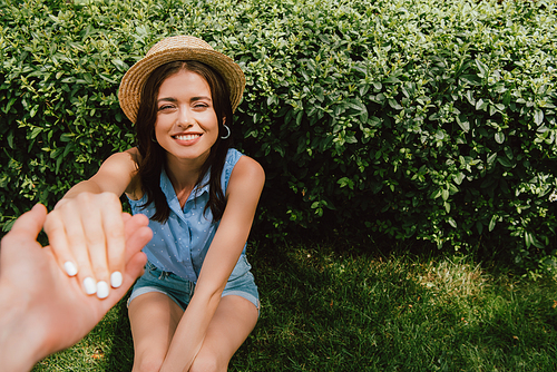 selective focus of man holding hands with cheerful girl in straw hat