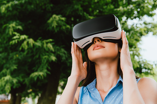 low angle view of young woman touching virtual reality headset outside