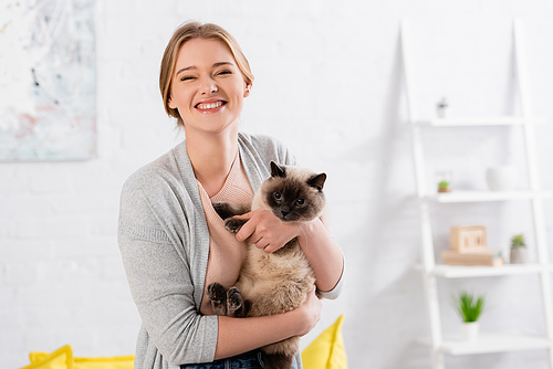 Happy woman  while holding siamese cat