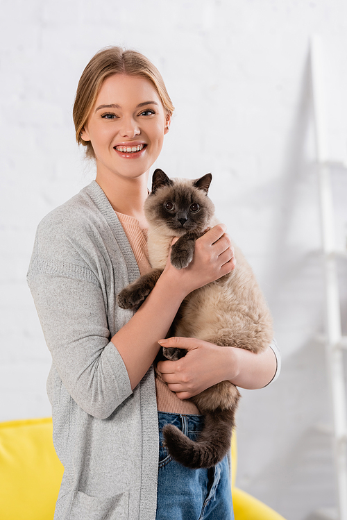Happy woman  while holding siamese cat at home
