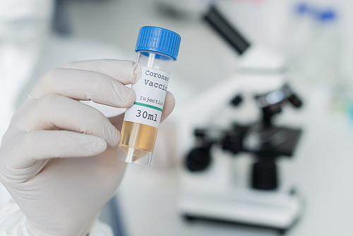 Cropped view of scientist in latex glove holding coronavirus vaccine in laboratory