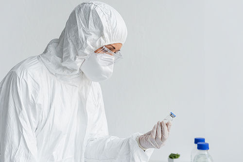 Scientist in hazmat suit holding vaccine in laboratory