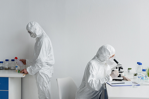 Scientists in hazmat suits working with vaccines in laboratory