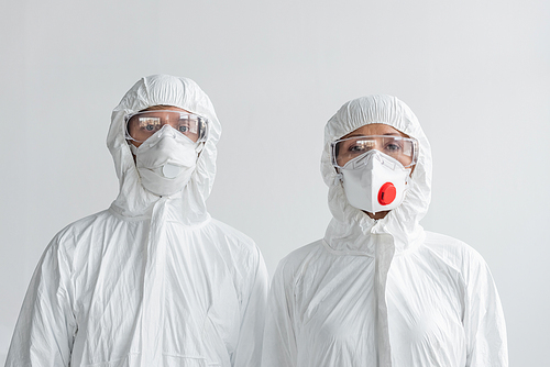 Scientists in hazmat suits and masks  isolated on grey