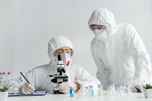 Scientists researching vaccine and writing on clipboard in laboratory