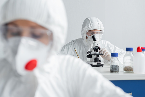 Scientist using microscope while working near colleague on blurred foreground