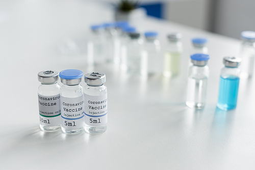 Jars with coronavirus vaccine lettering on table in laboratory