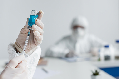 Scientist picking up vaccine in syringe in laboratory