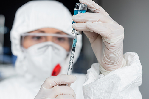Scientist on blurred background picking up vaccine in syringe