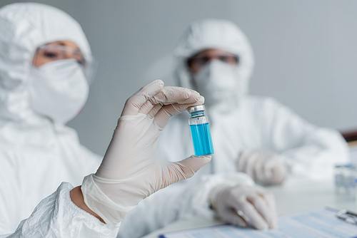 Vaccine in hand of scientist working with colleague in laboratory
