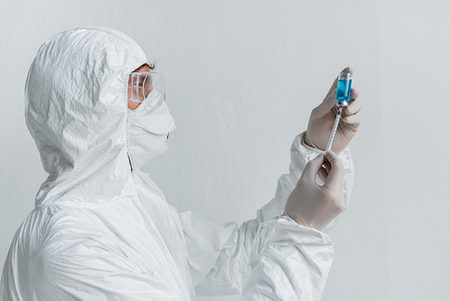 Scientist picking up vaccine form jar in syringe