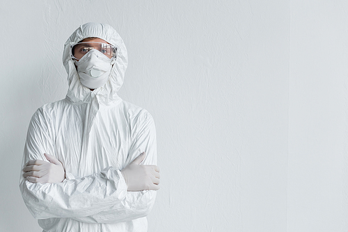 Scientist in hazmat suit and protective goggles  with crossed arms