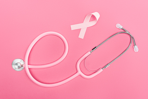 top view of stethoscope and pink breast cancer sign on pink background
