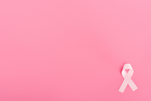 top view of pink ribbon on pink background with copy space, breast cancer concept