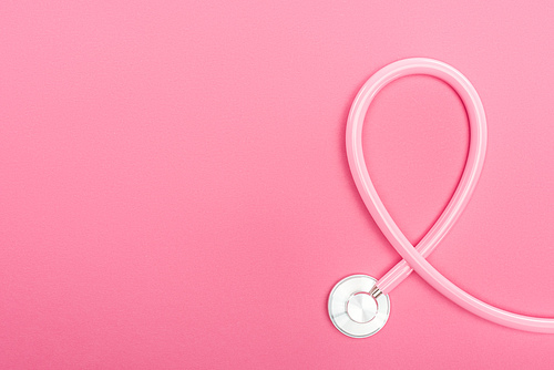 top view of pink stethoscope on pink background with copy space