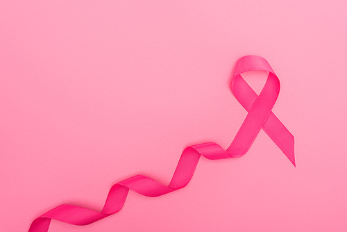 top view of curved crimson breast cancer sign on pink background