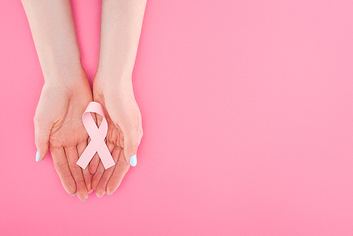partial view of woman with pink breast cancer sign on pink background with copy space