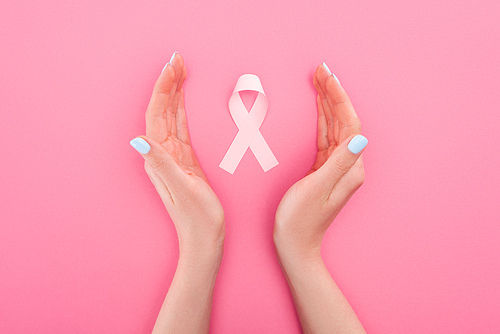 partial view of female hands near pink breast cancer sign on pink background