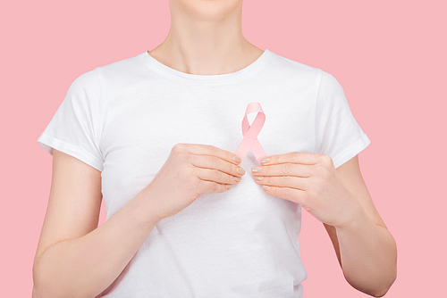 partial view of woman in white t-shirt holding pink breast cancer sign isolated on pink