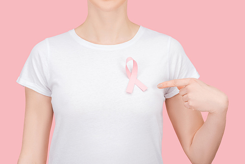 partial view of woman in white t-shirt pointing with finger at pink breast cancer sign isolated on pink