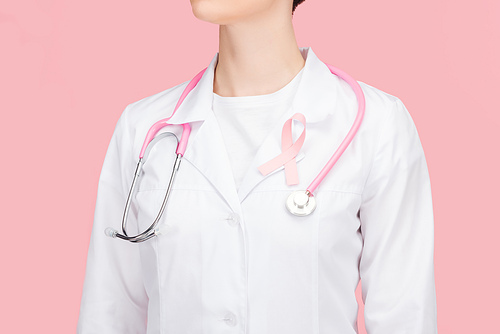 cropped view of doctor in white coat with pink breast cancer sign and stethoscope isolated on pink