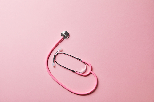 top view of pink stethoscope on light pink background