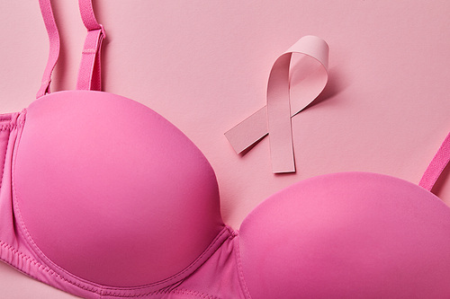 ribbon near bra on light pink background, breast cancer concept