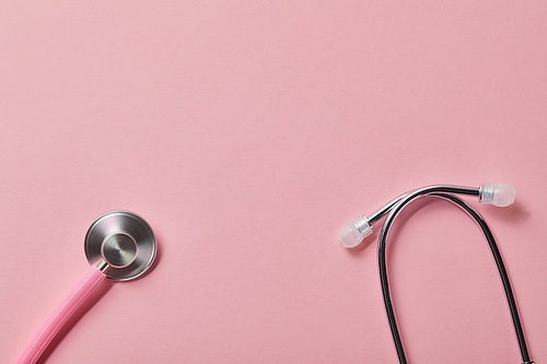top view of pink metal stethoscope on light pink background