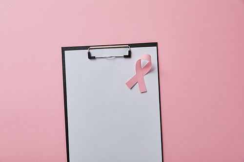 breast cancer ribbon on folder with empty paper isolated on pink