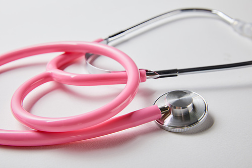 selective focus of pink stethoscope on white surface