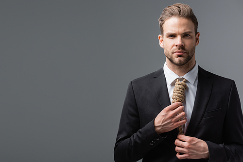 frustrated businessman  and touching tie made of rope isolated on grey