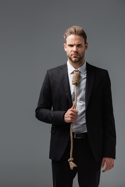 tense businessman in black suit, with rope instead of tie,  isolated on grey