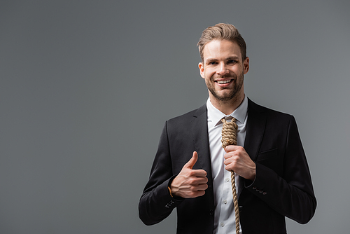 happy businessman with rope instead of tie showing thumb up isolated on grey