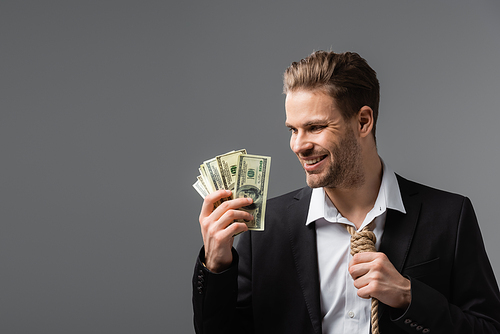 happy businessman with tie made of rope holding dollar banknotes isolated on grey