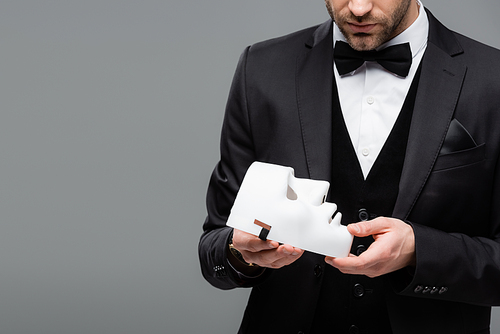 partial view of elegant businessman holding face mask isolated on grey