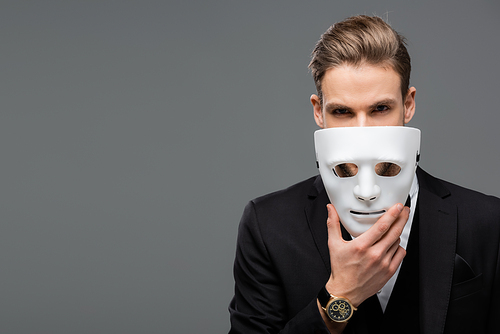 businessman holding mask near face while  isolated on grey