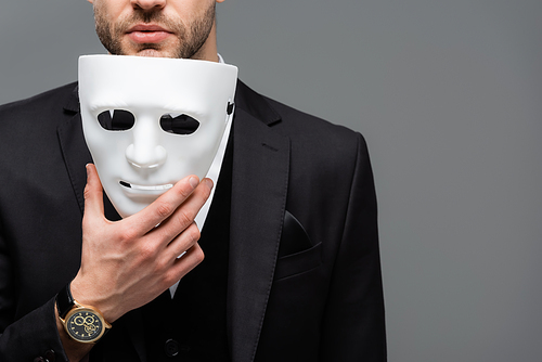 cropped view of businessman holding face mask isolated on grey