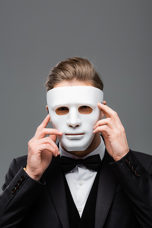 young businessman hiding face with mask isolated on grey