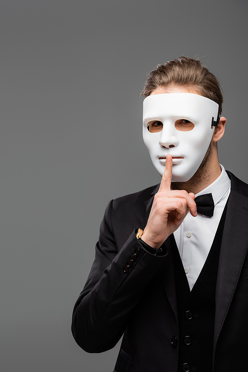 businessman in face mask showing hush sign isolated on grey