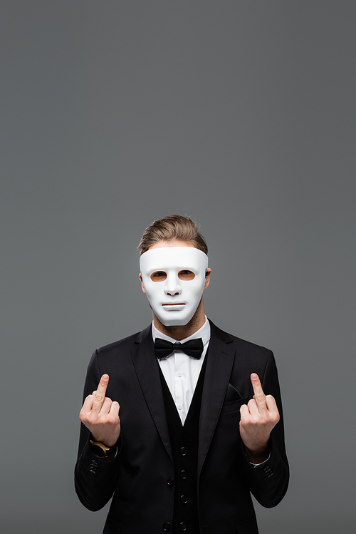 businessman in face mask showing middle fingers isolated on grey
