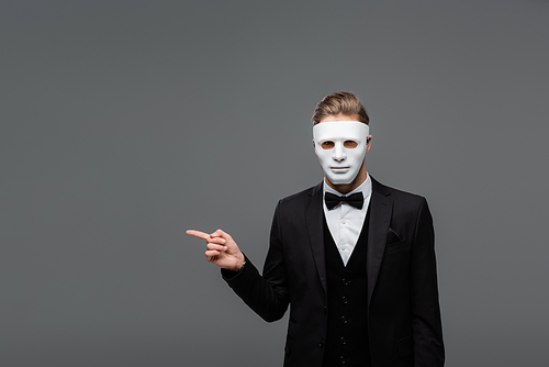 elegant businessman in face mask pointing with finger isolated on grey