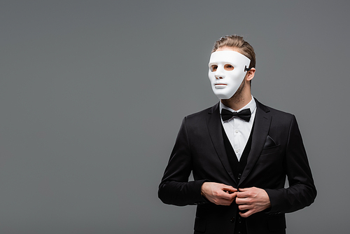 businessman in face mask buttoning blazer isolated on grey