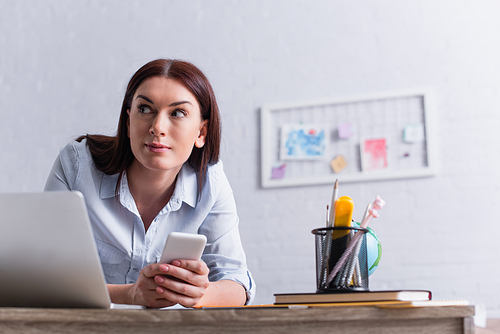 woman taking smartphone while sneaking around at workplace