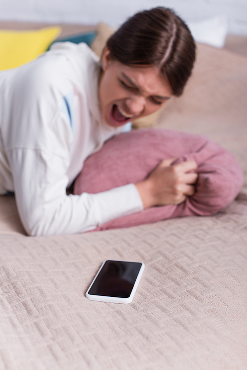 blurred teenage girl screaming near smartphone with blank screen
