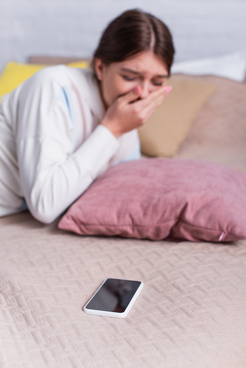 smartphone with blank screen near upset teenage girl on blurred background