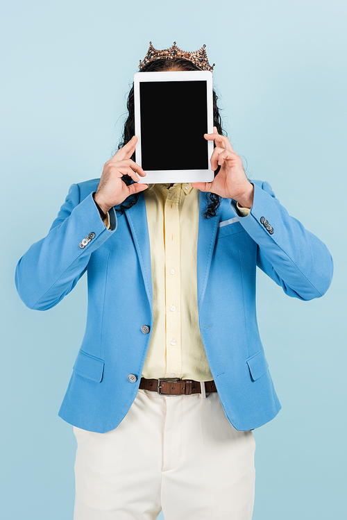 man in jacket and crown covering face while holding digital tablet with blank screen isolated on blue