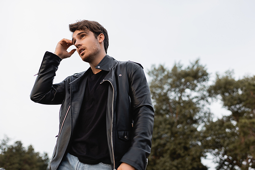 Low angle view of man in leather jacket looking away outdoors