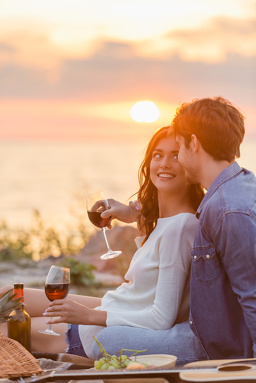 Selective focus of young couple holding glasses of wine near acoustic guitar