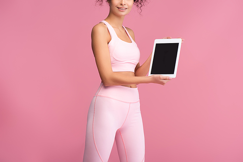 cropped view of young sportswoman holding digital tablet with blank screen isolated on pink