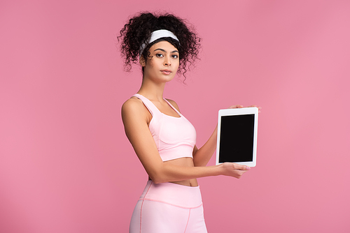 young sportswoman holding digital tablet with blank screen isolated on pink